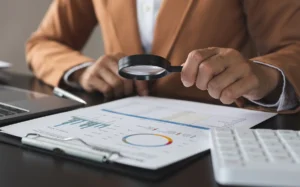 Person reviewing financial documents with a magnifying glass